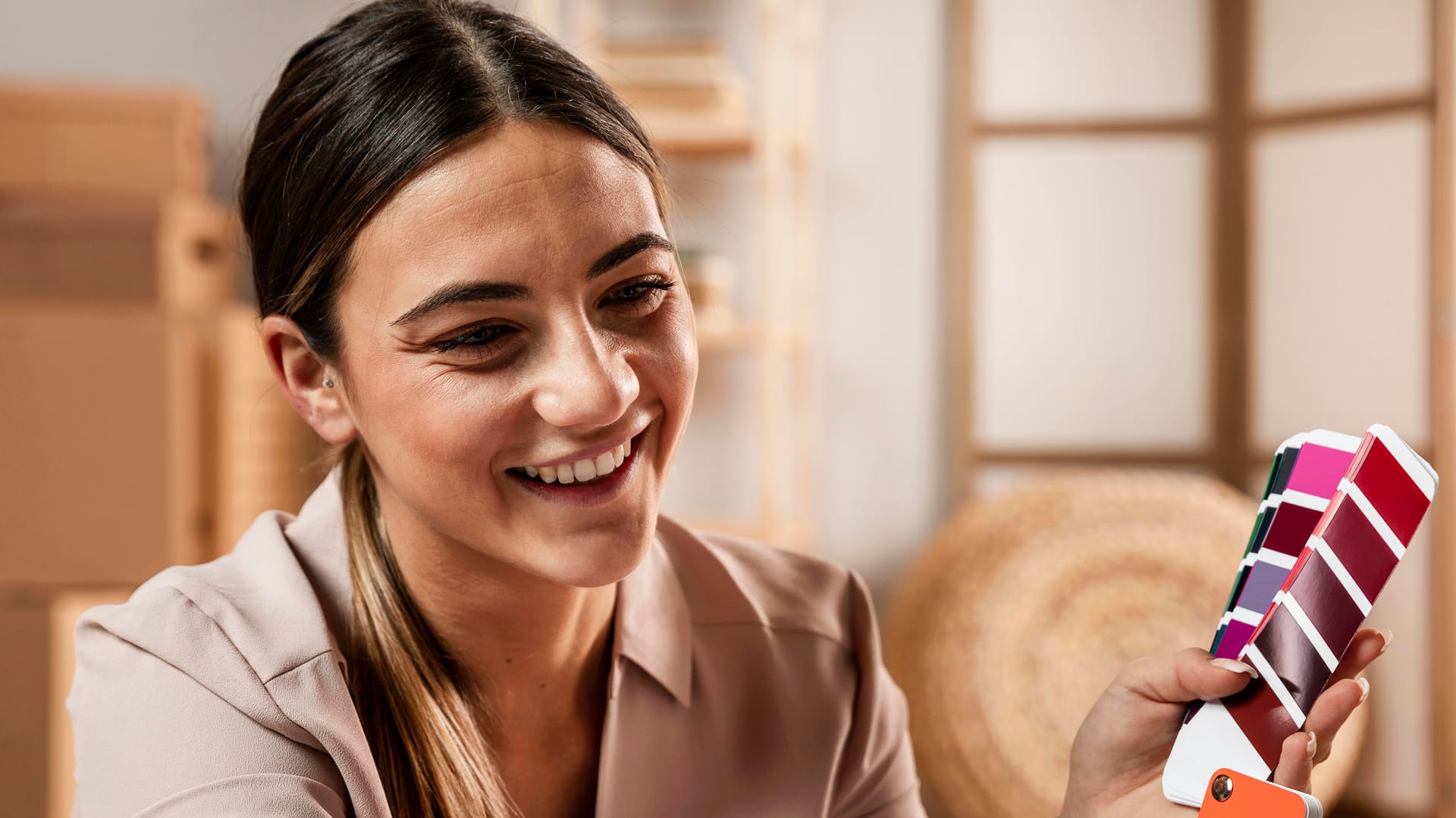 Designer sorrindo ao escolher cores em um leque de paleta para uma identidade visual